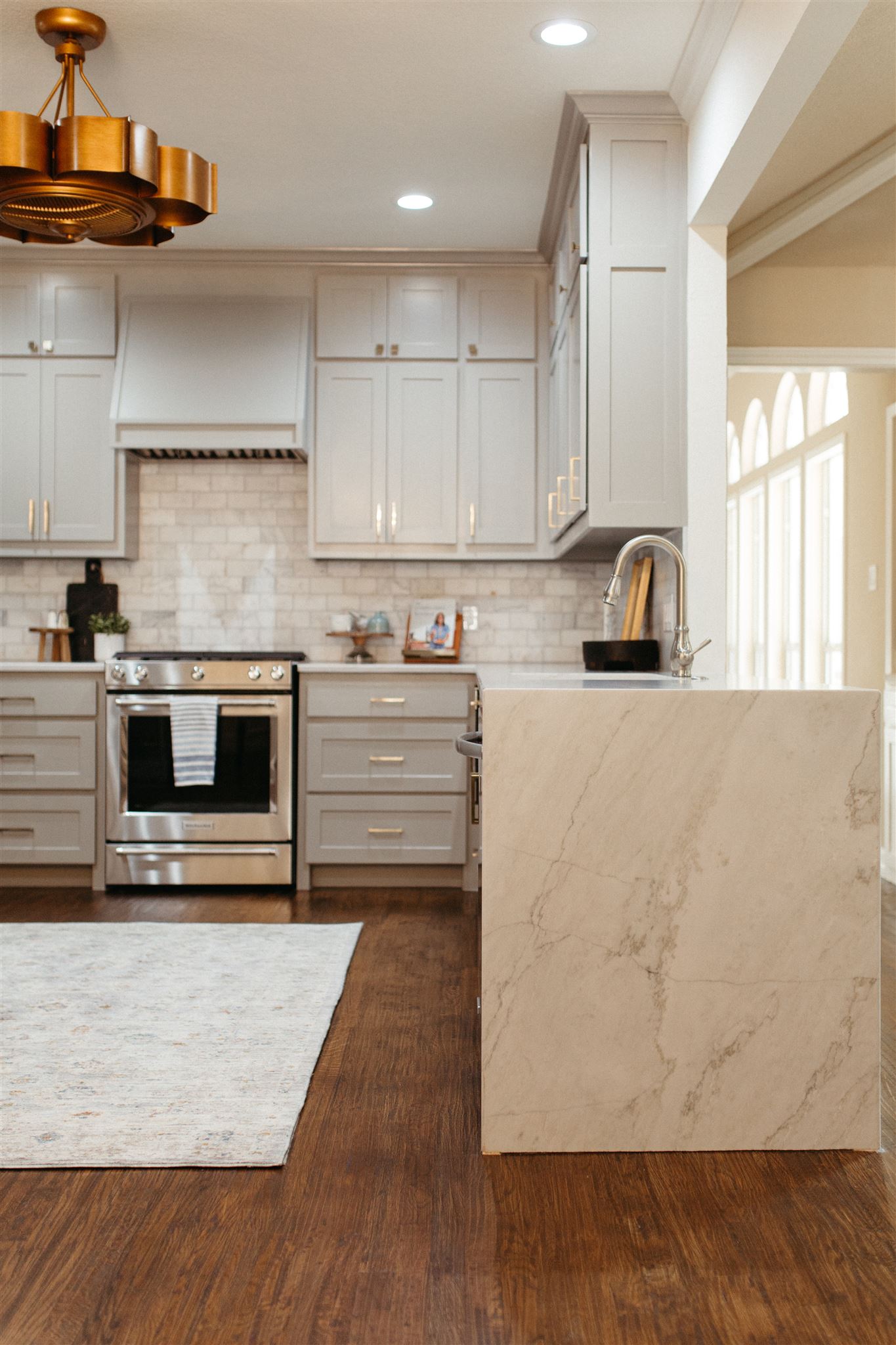 Kitchen with waterfall countertop and brass hardware